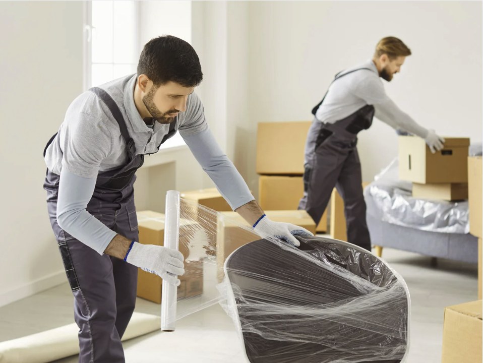 Pracownik Przenosiny zabezpiecza mebel folią stretch